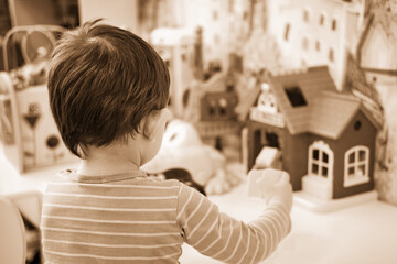 Toddler baby is playing with toys in kindergarten. Happy child boy in the playroom. Kid aged one...