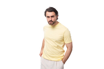 a young well-groomed European brunette guy with a beard and mustache is dressed in a yellow T-shirt in a summery way