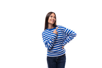 young caucasian woman with dark hair dressed in a blue striped sweatshirt points her hand to the side on a white background