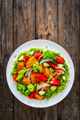 Seared chicken nuggets with vegetable salad on tortilla on wooden background
