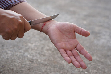 Closeup depressed man use knife to cut his wrist. Concept, depression, panic, mental or physical...