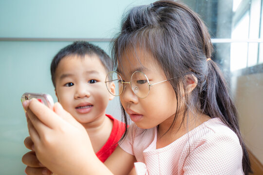 Sister and brother child playing smartphone in room