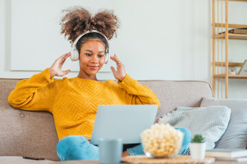 African American teenage women sitting on sofa listening to music enjoying meditation for sleep and...