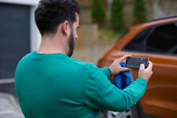 man taking photos on a smartphone of a car preparing for sale  - obrazy, fototapety, plakaty