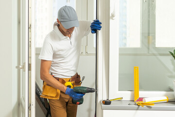 a repairman repairs, adjusts or installs metal-plastic windows in the apartment. glazing of...