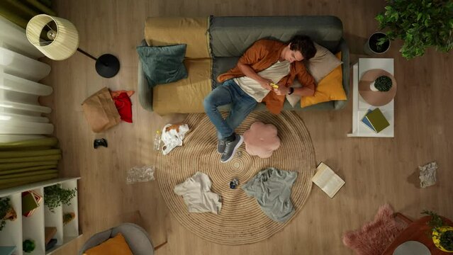 Top view shot of a homosexual male couple. The man enters the room and sees his partner sitting on the couch. He starts scolding about the mess he left around.