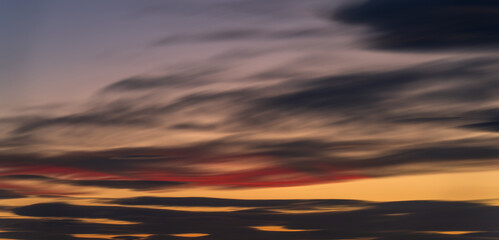 Naklejka na ściany i meble Peaceful Dusk: A Long Exposure of Clouds at Sunset