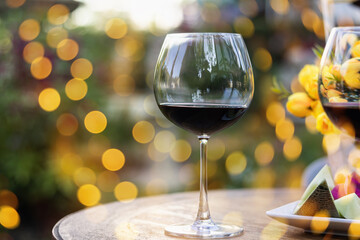 A glass of red wine on table with blur light in restaurant.