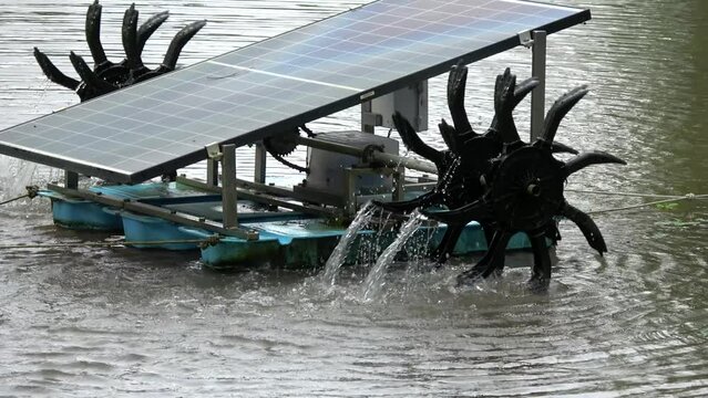 Zoom out view of solar panels powering two water wheels to pump water away for agricultural purpose clean green renewable way to use sustainable resources for farming 4k high resolution footage