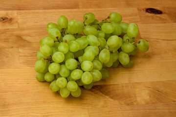 Izolowana kiść zielonych dojrzałych winogron leży na drewnianym stole