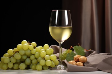 Glass of white wine with grapes on old wooden table