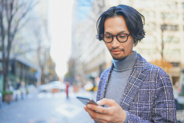 街中でスマートフォンを使うジャケットを着た男性