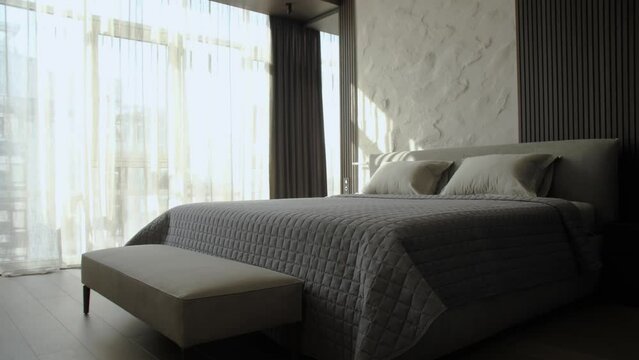 Dolly shot of front view of bedroom entrance, sun rays trough the window in large bedroom, bedding, gray blanket slow motion.