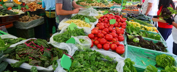 greengrocer in the fruit and vegetable market stall selling fresh fruit and vegetables
