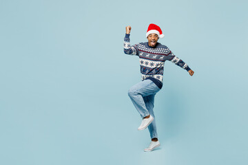 Full body young man wear sweater Santa hat posing do winner gesture celebrate clench fists say yes...