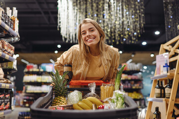 Young satisfied customer woman wear casual clothes look camera shopping at supermaket store grocery...