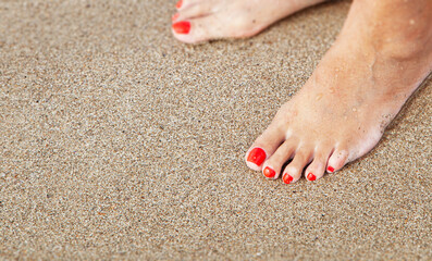 Women's feet with a pedicure in the sand on the beach