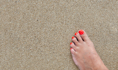 Women's feet with a pedicure in the sand on the beach