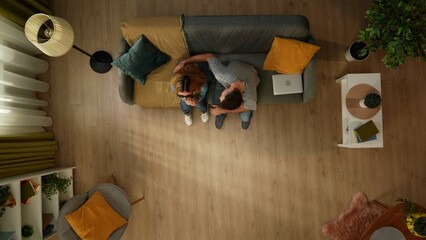 Top view shot of a man sitting on the couch with his partner, a woman with sight impairment. She...