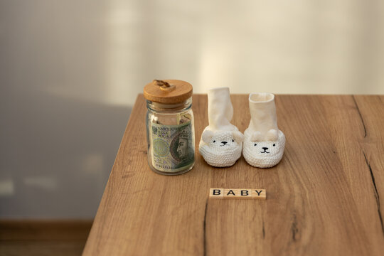 białe skarpetki położone na stole a obok napis dziecko zwiastujący wczesne przyjście dziecka na świat i radość rodzic&oacute;w. Koncept demografii kraju i problemy związane z tym tematem