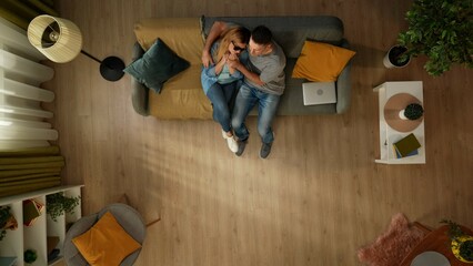 Top view shot of a man sitting on the couch with his partner, a woman with sight impairment. She expresses her anxiety about something, a man tries to support and cheer her up.