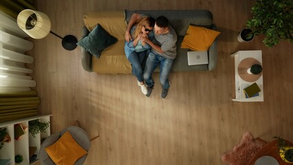 Top view shot of a man sitting on the couch with his partner, a woman with sight impairment. She...