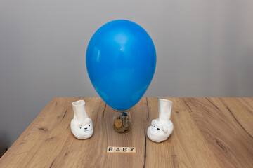 Jar with a balloon inside, containing euro with tiny baby socks in white, shaped like lambs. An economic and parenting concept, reflecting state social programs and the costs associated with raising c