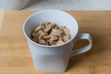 The cubed bun is soaked in milk in a mug.