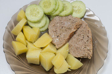 Boiled potatoes and meatloaf on a plate.