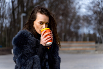 A Stylish Woman Enjoying a Refreshing Beverage in a Luxurious Fur Coat
