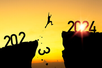 Welcome merry Christmas and happy new year in 2024,Silhouette Man jumping from 2023 cliff to 2024...
