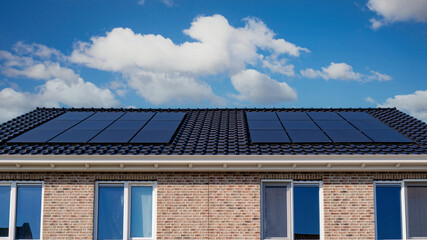 Newly built houses with black solar panels on the roof against a sunny sky Close up of new building...