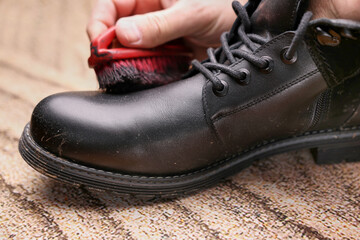 Black leather boots are cleaned with shoe cream. The concept of shoe care.