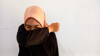 a woman in a headscarf was coughing, covering her mouth with her elbow.