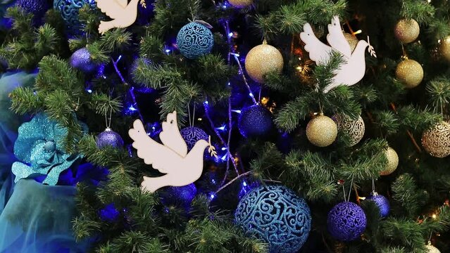 Christmas tree. Christmas decorations on an artificial spruce branch close-up. Beautiful blue and golden Christmas balls, a dove as a symbol of peace