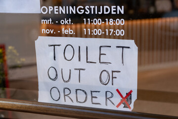Toilet out of order sign on the front window of a cafe