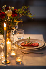 holidays, dinner party and celebration concept - close up of festive table serving with flowers in vase and candles burning at home on valentine's day