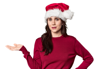 Young woman in Santa hat and red sweater showing a copy space on a palm and holding another hand on waist.