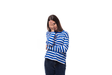 young upset european brunette woman dressed in striped blue clothes on a white background
