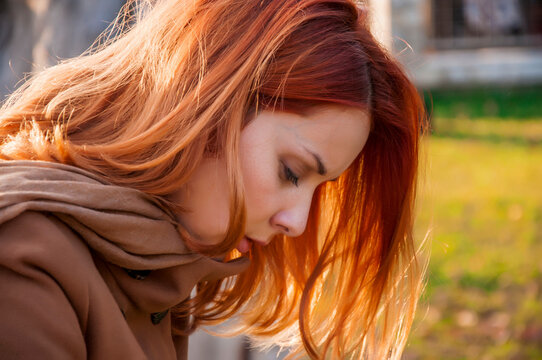 Portrait of a young attractive long haired woman with red hair in nature