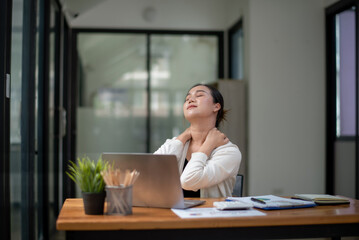 Businesswoman stretching lazy at the desk to relax while working in the office. Feeling stressed and achy from work.