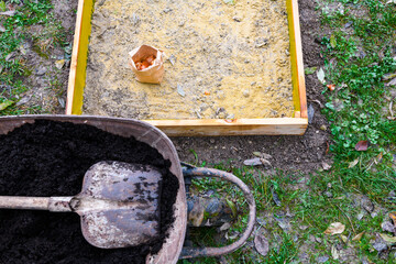 Planting tulip bulbs in a raised bed. Adding compost to flowerbed. Growing tulips. Fall gardening jobs background.