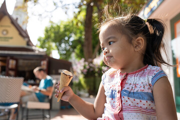 Happy asian preschool girl enjoying eat icecream travel in summer city