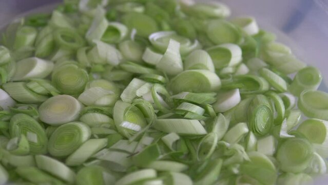 Chopped leeks for cooking are washed in a bowl,