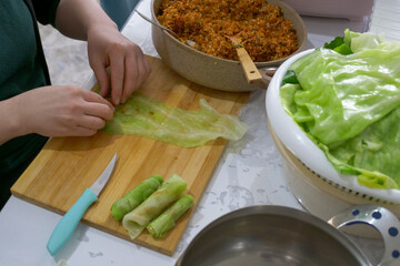 The woman making stuffed cabbage carefully puts the bulgur mixture into the cabbages and wraps them.