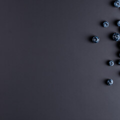 Minimalistic background with blueberries. Blueberries on dark minimalistic background. Wallpaper, template, background with bright blueberries. Background with berries.