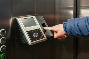 The man put his finger in the Fingerprint Access Control Terminal with face recognition function installed in the elevator of the business center