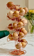 Spiral egg holder filled with fresh eggs on kitchen table