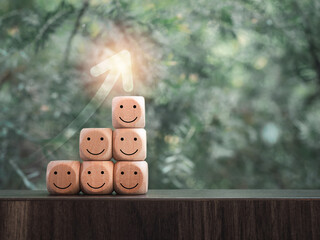 Rising up arrow on wooden cube blocks as a business graph or chart steps with happy smile faces on...