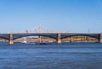Powerful pusher tugboat with barges of petroleum products under Eads Bridge in St Louis, Missouri - obrazy, fototapety, plakaty